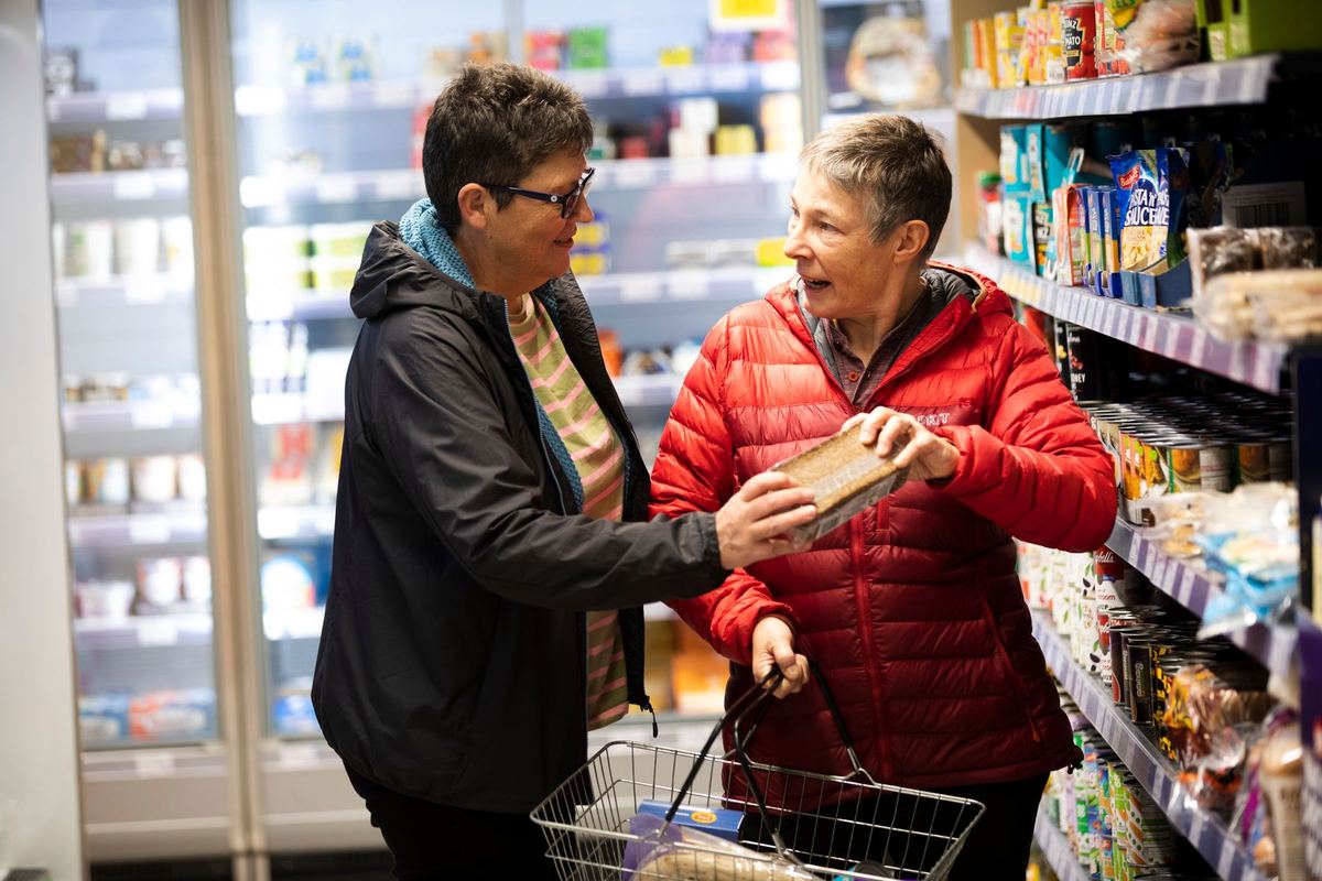 Two older women choosing a product together in a supermarket